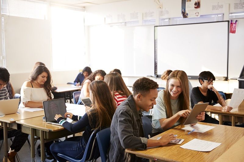 Wide-Angle-View-Of-High-School-Students-Sitting-At-Desks-In-Classroom-Using-Laptops-cm